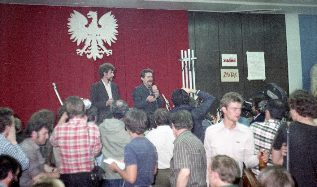 1980 年 8 月 31 日的格但斯克造船廠職安廳;簽署協議的場所與罷工者要求的紀念物在同一歷史場景中留下痕跡。