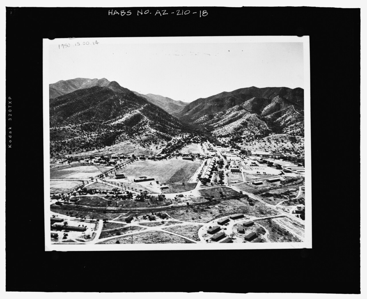 AERIAL PHOTOGRAPH TAKEN IN 1950, LOOKING TO THE SOUTH. THE 1916 STABLES ARE LOCATED IN THE MIDDLE RIGHT PORTION OF THE PHOTOGRAPH (FORT HUACHUCA HISTORICAL MUSEUM, PHOTOGRAPH 1950.15.00 HABS AZ-210-18.tif