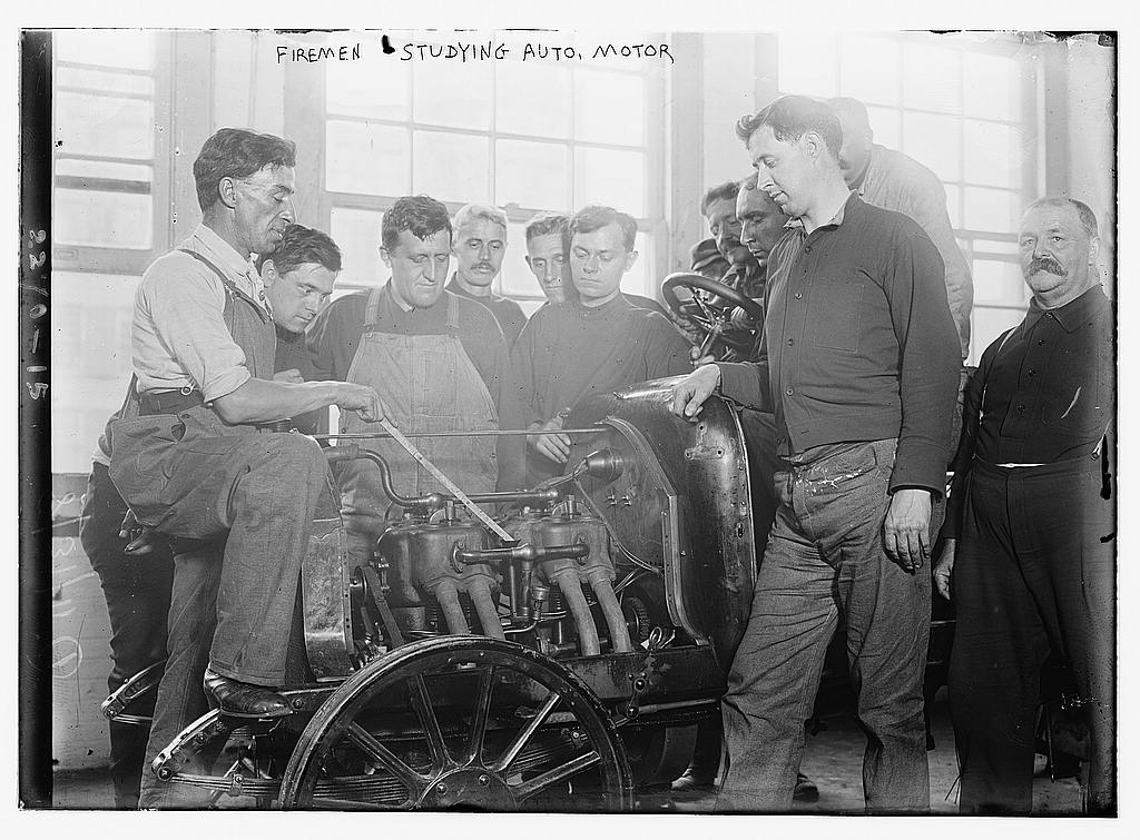Firemen studying auto motor LOC 2162899383